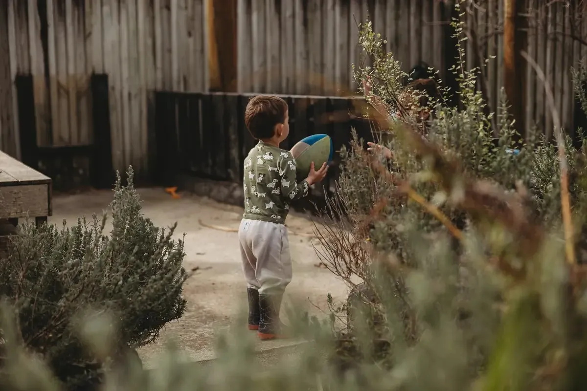 A child playing with a ball among the garden plants