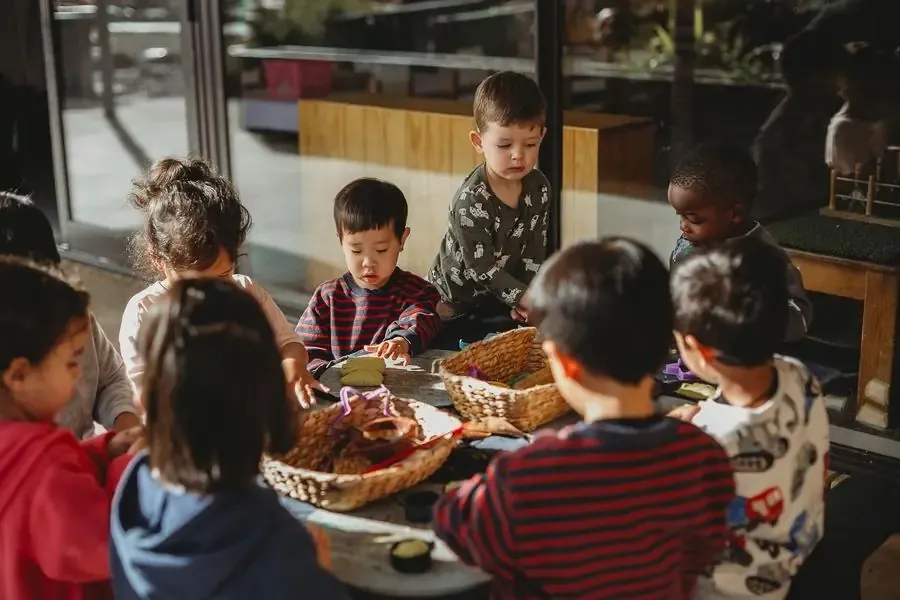 A teacher and children sharing time around a table at Canopy