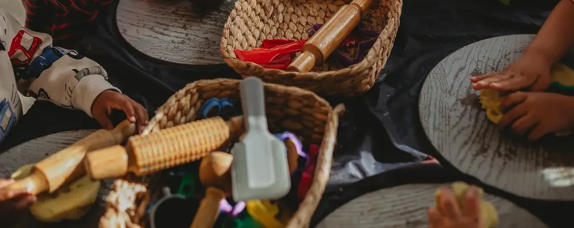 Hands sharing natural materials and tools around a Canopy activity table